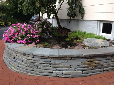 Landscape Design, water feature, stack stone wall with landscape lighting in Rochester, (NY) by Acorn Ponds & Waterfalls- Landscape ideas for your outdoor living. Image